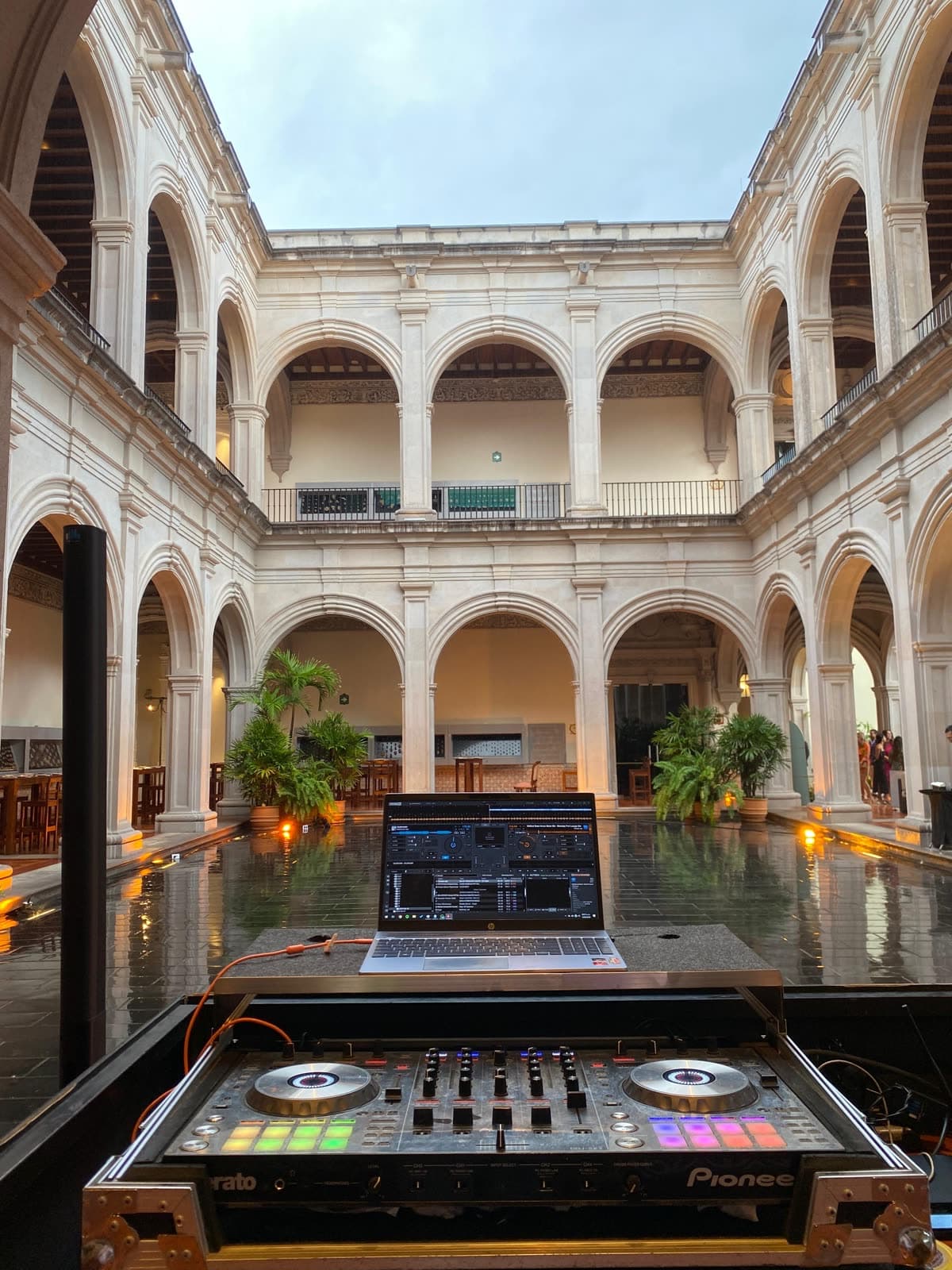Consola de DJ y audio Bose en patio colonial con espejo de agua