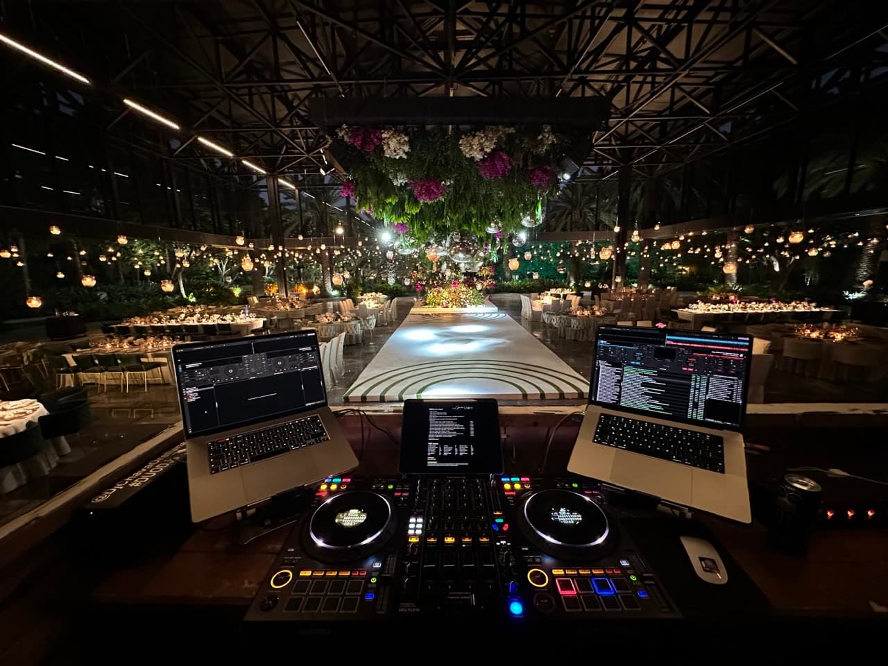 Cabina del DJ con vista a la pista iluminada llena de invitados