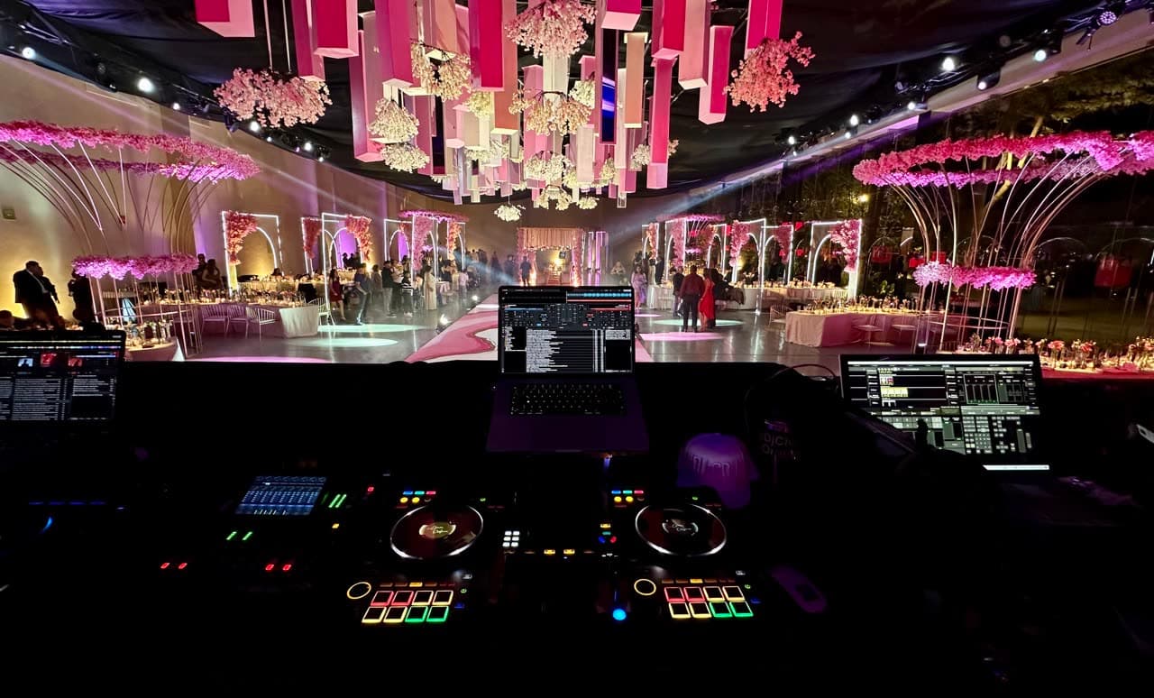 Cabina de DJ profesional con controladores en venue con florales colgantes