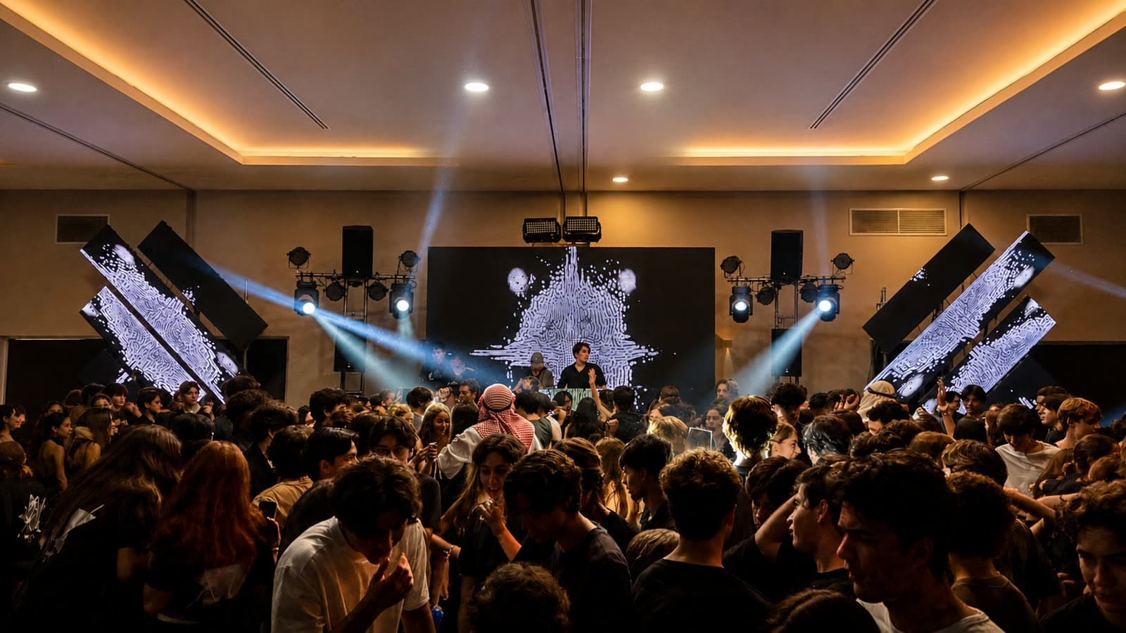 Salón de eventos lleno de invitados bailando bajo haces de luz y pantallas