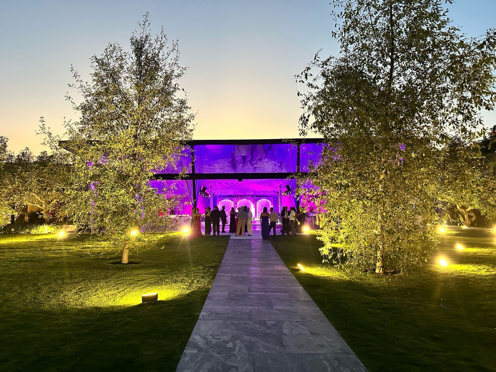 Iluminación arquitectónica magenta sobre fachada y jardín de venue de eventos en Guadalajara