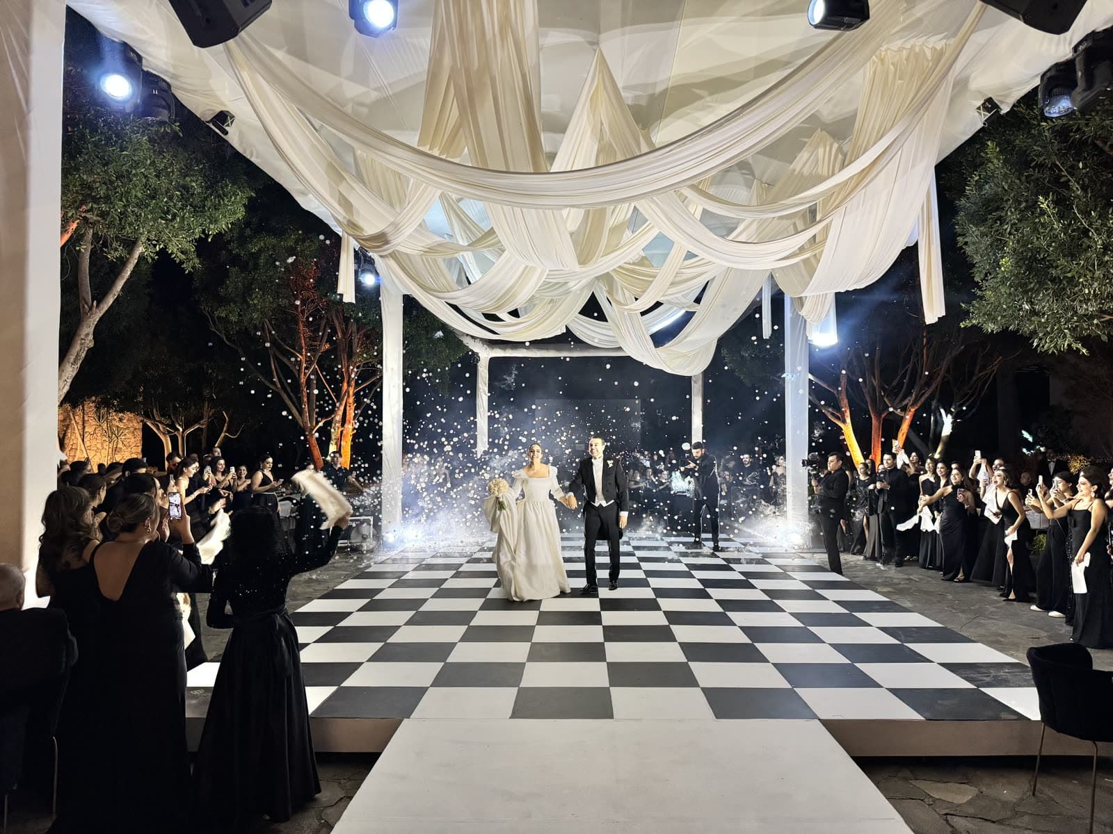 Novios entrando a pista de baile de ajedrez entre chispas frías en boda de noche en Guadalajara