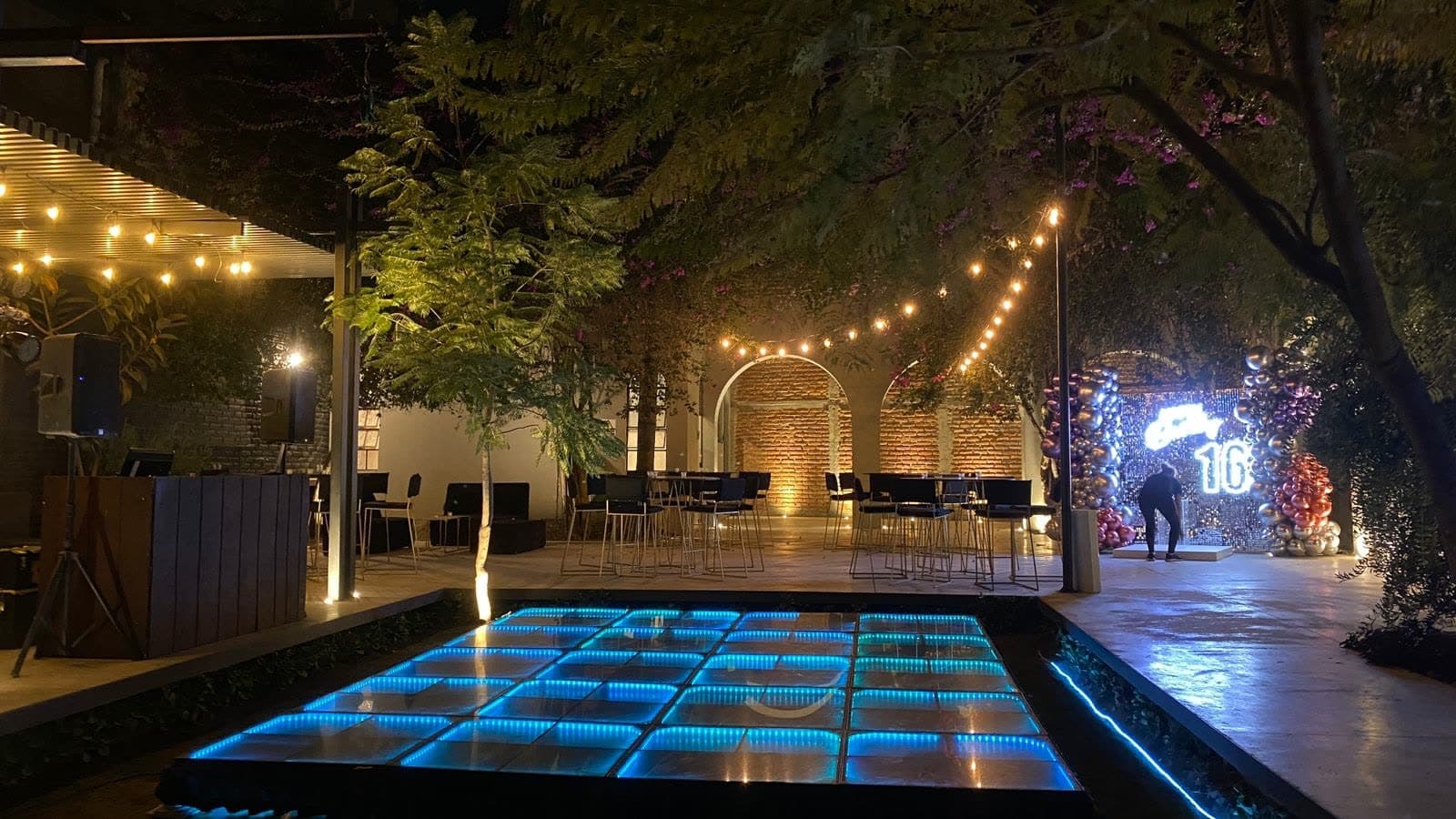 Pista de cristal iluminada en color aqua en jardín nocturno con series de luces